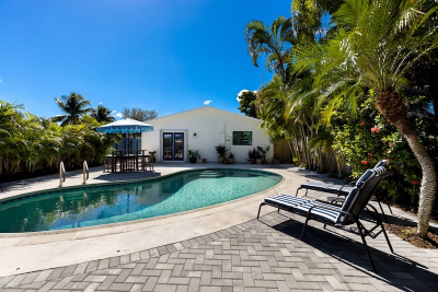 Pool deck resurfacing cost considerations for a backyard pool with gray pavers, lounge chairs, and tropical landscaping
